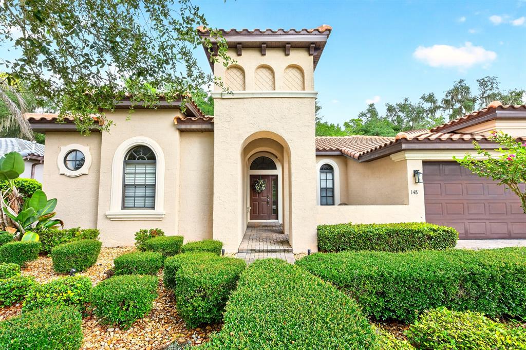 A beige stucco house with a central tower, arched entryway, and a brown garage door — 148 VERDE WAY, DEBARY, FL