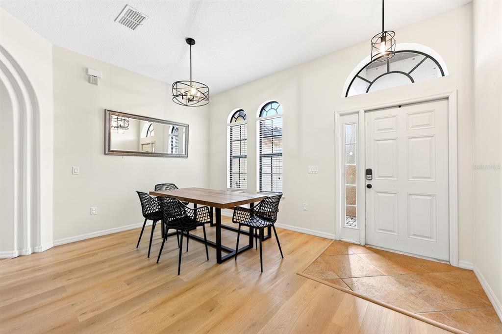 A dining area features light wood floors, a wooden table, black chairs, and a front door — 148 VERDE WAY, DEBARY, FL