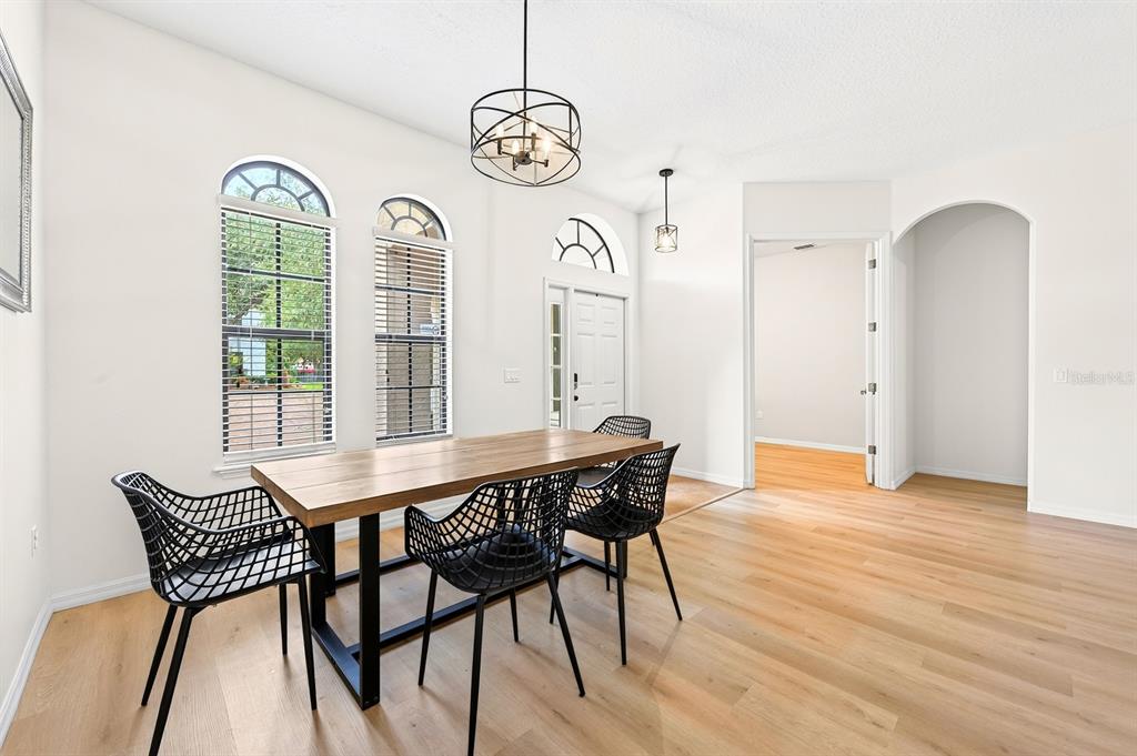 A dining area features a wooden table, black chairs, light wood flooring, and arched windows — 148 VERDE WAY, DEBARY, FL