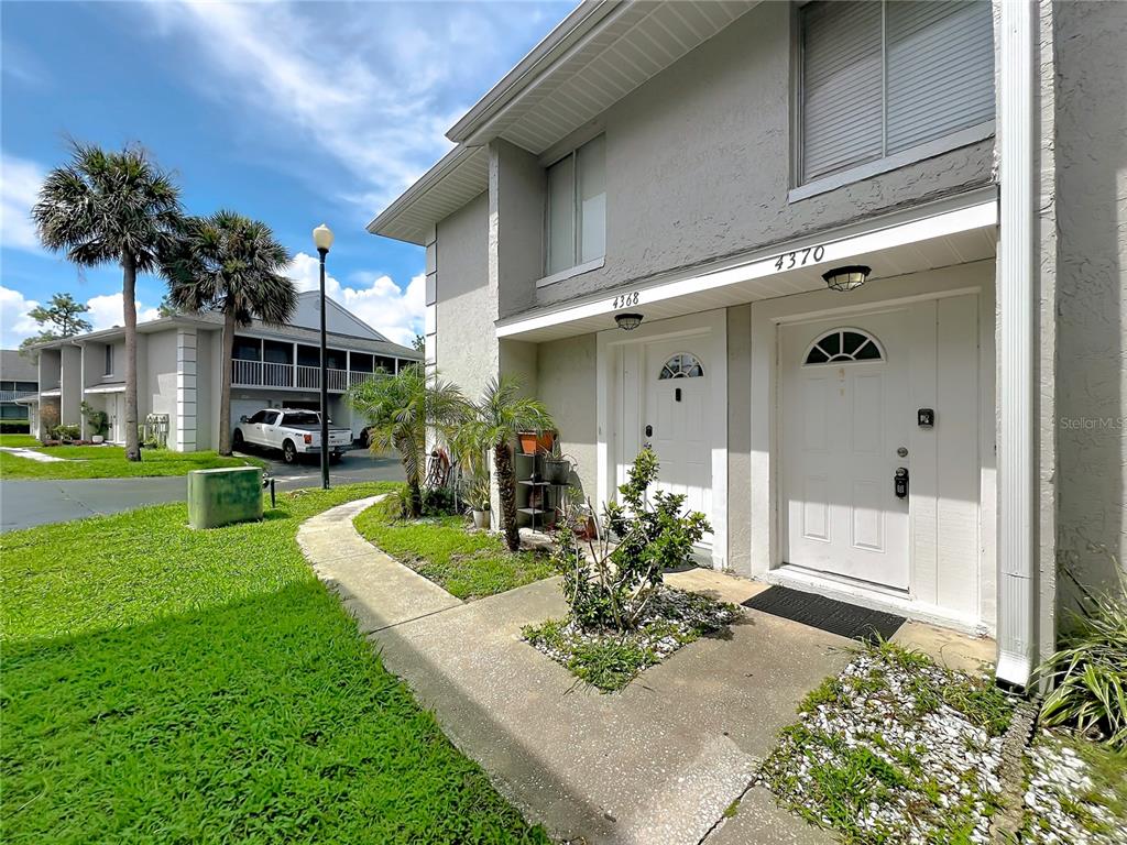 A two-story building exterior features four garage doors on the ground level and a screened balcony — 4370 WHITE PINE AVENUE UNIT 2, ORLANDO, FL