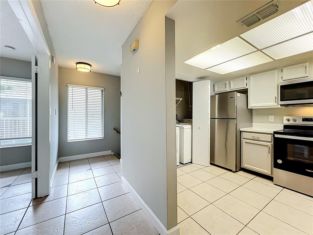 A view of a tiled entryway leading to a kitchen with white cabinets and appliances — 4370 WHITE PINE AVENUE UNIT 2, ORLANDO, FL