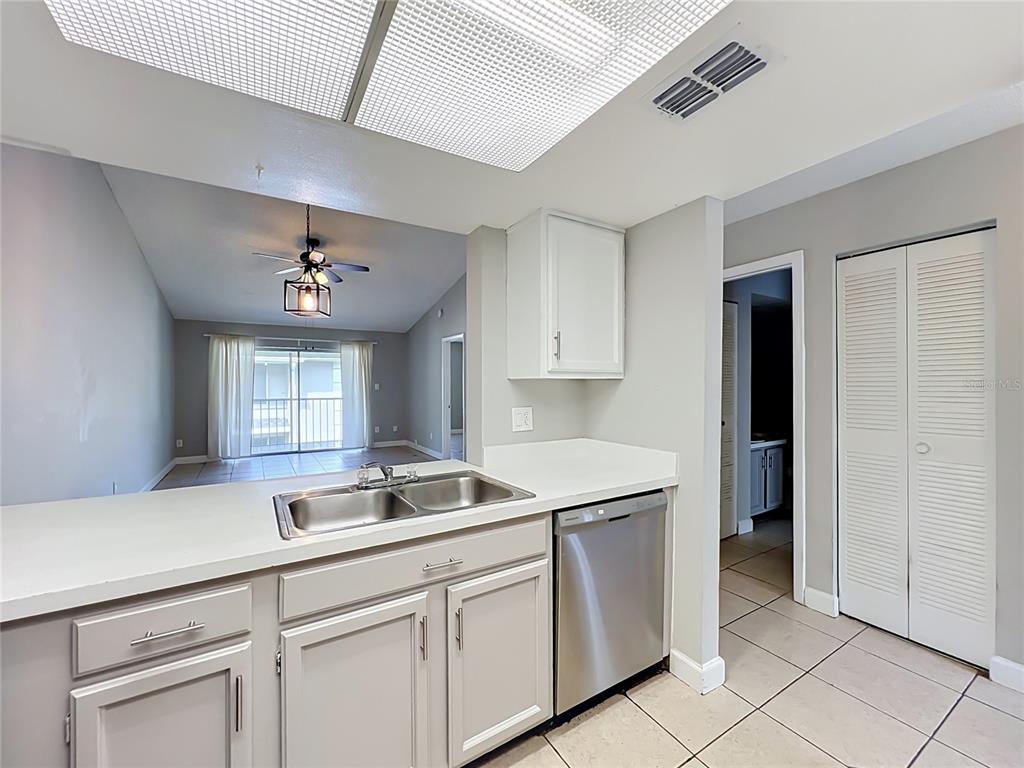 A view from a tiled room looking into a kitchen with white cabinets and appliances — 4370 WHITE PINE AVENUE UNIT 2, ORLANDO, FL