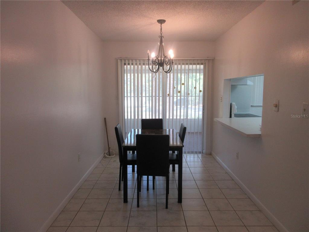 A dining room features tile flooring, a dark wood table with chairs, and sliding doors — 2410 SE 16TH AVENUE UNIT H, OCALA, FL