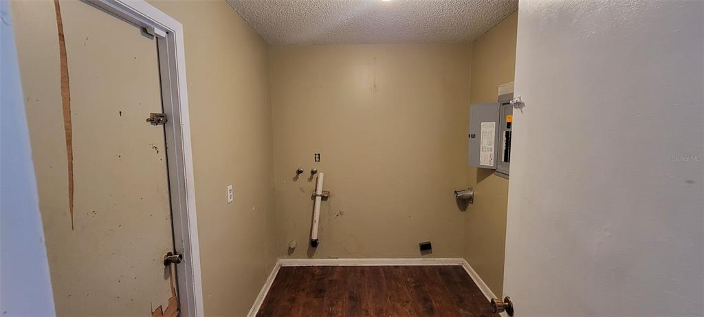 A laundry room with wood-look flooring, plumbing hookups, and an open electrical panel — 1425 NE OLD MILL DRIVE, DELTONA, FL