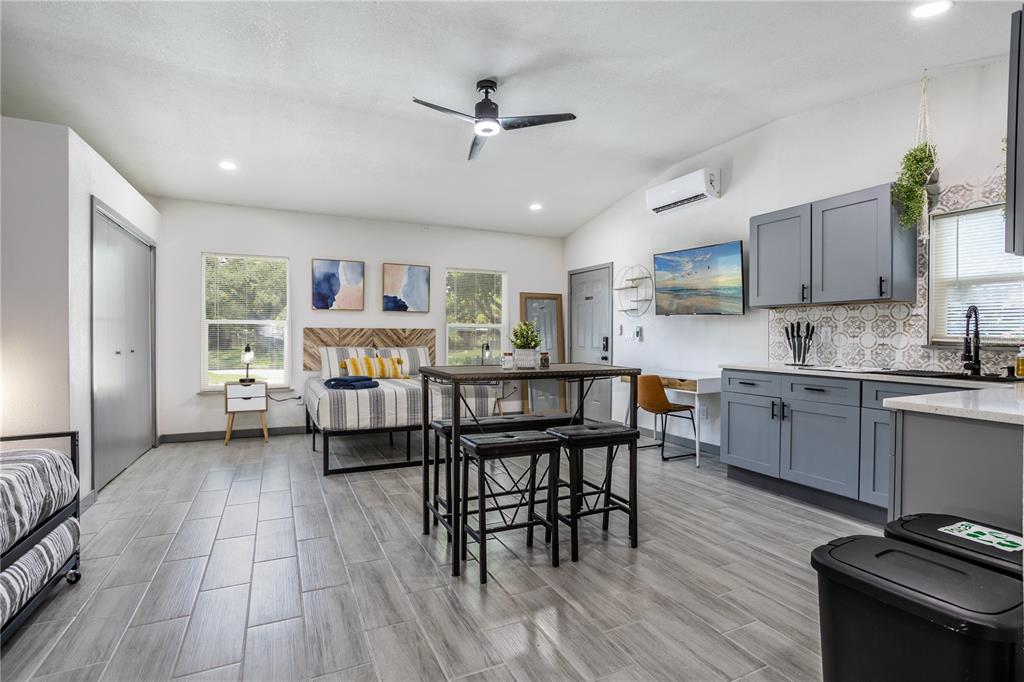 A studio apartment features a bed, dining table, kitchenette with gray cabinets, and tile flooring — 1213 CORBETT LANE UNIT 2, ORLANDO, FL