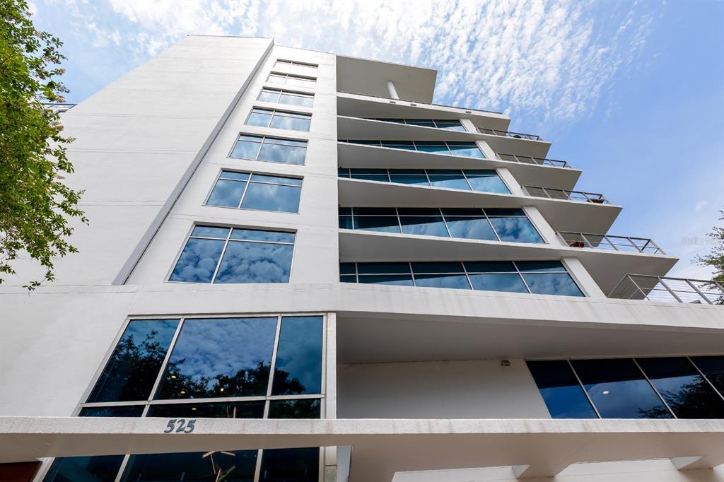 A low-angle view of a modern white mid-rise building with glass windows and balconies — 525 E JACKSON STREET UNIT 507, ORLANDO, FL
