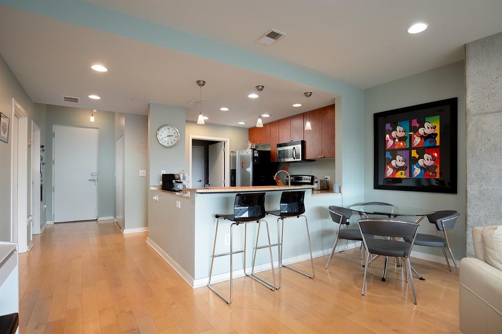 An open-concept kitchen features a breakfast bar with two stools, a dining table, and hardwood floors — 525 E JACKSON STREET UNIT 507, ORLANDO, FL