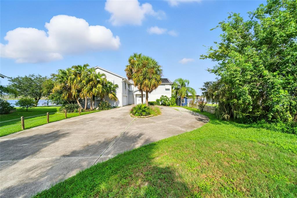 A circular concrete driveway leads to a two-story house surrounded by palm trees and greenery — 2435 N WATERSEDGE DRIVE, CRYSTAL RIVER, FL