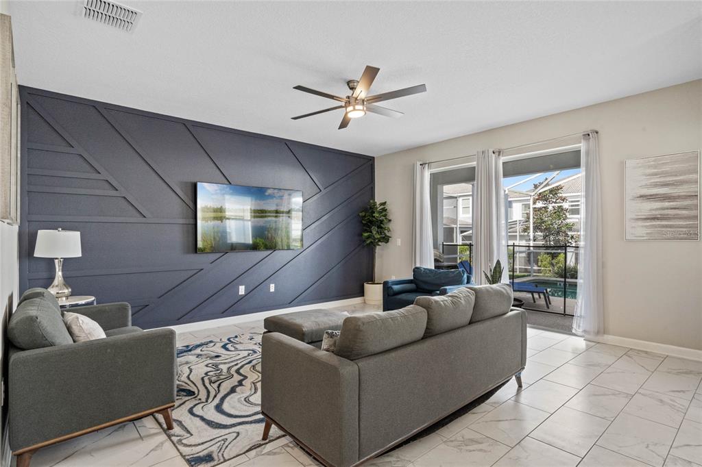 A living room features a dark blue accent wall with geometric molding and tile flooring — 1565 MULLIGAN BOULEVARD, DAVENPORT, FL