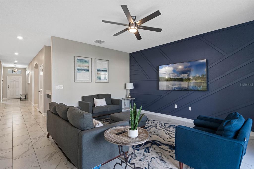 A living room features a dark blue accent wall with geometric molding and tiled floors — 1565 MULLIGAN BOULEVARD, DAVENPORT, FL