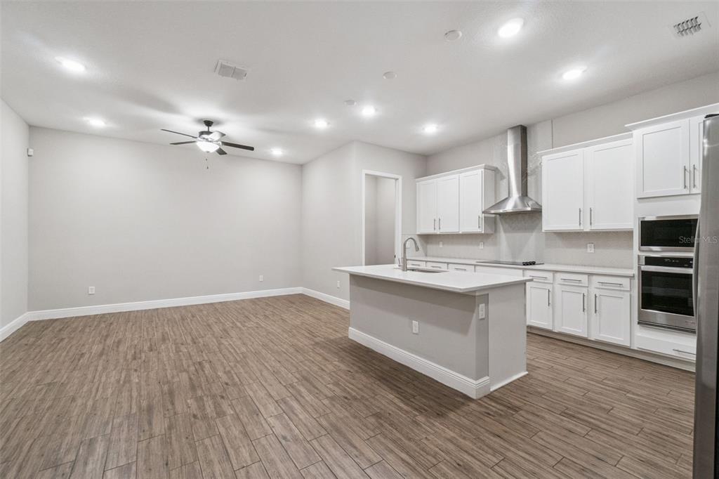 A modern kitchen with white cabinets, a center island, and wood-look tile flooring — 6447 CYRILS DRIVE, ST CLOUD, FL