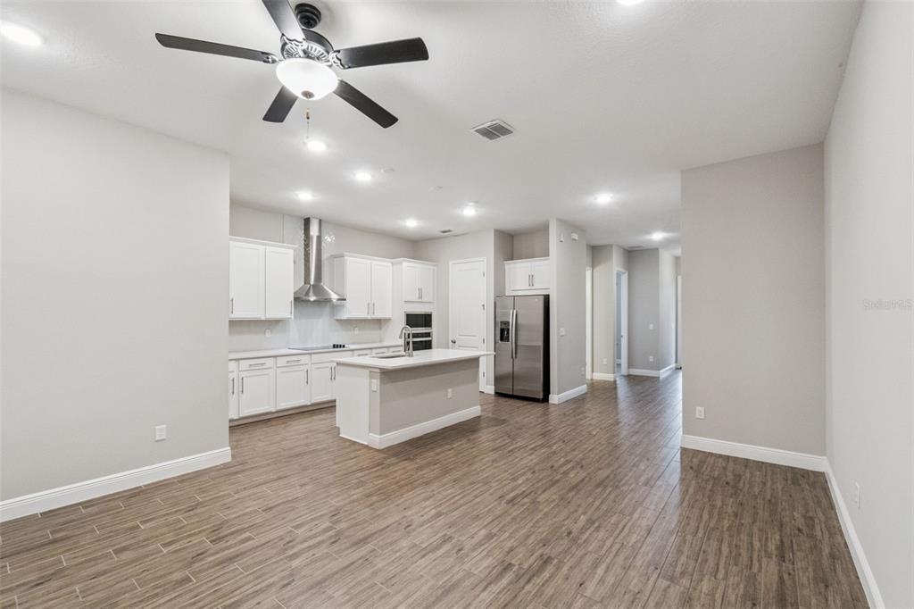 A modern kitchen with white cabinets, stainless steel appliances, and an island on wood flooring — 6447 CYRILS DRIVE, ST CLOUD, FL
