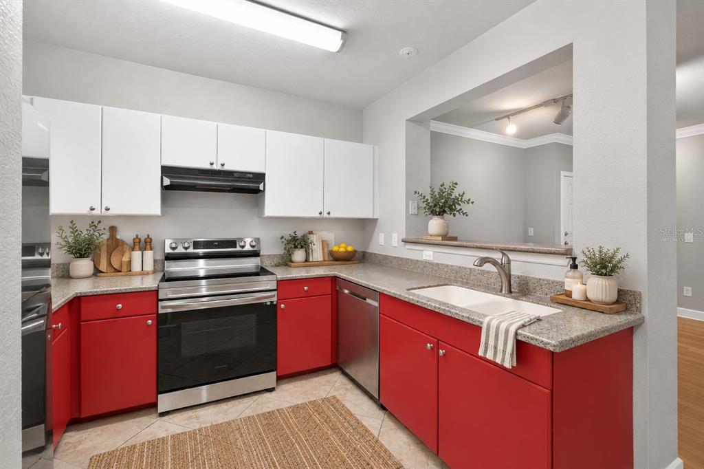 A kitchen features white upper cabinets, red lower cabinets, gray countertops, and stainless steel appliances — 300 E SOUTH STREET UNIT 2014, ORLANDO, FL