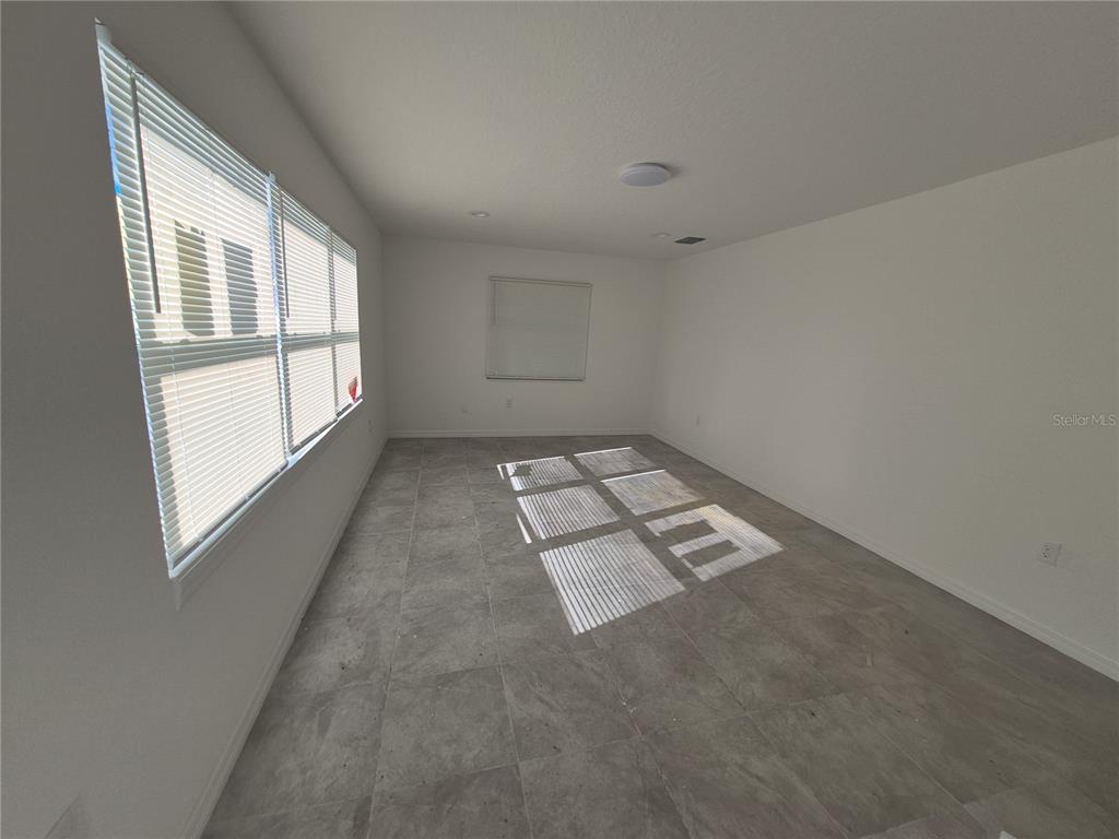 An unfurnished room with light tile flooring, white walls, and several windows with blinds — 6 S BARBOUR STREET, BEVERLY HILLS, FL