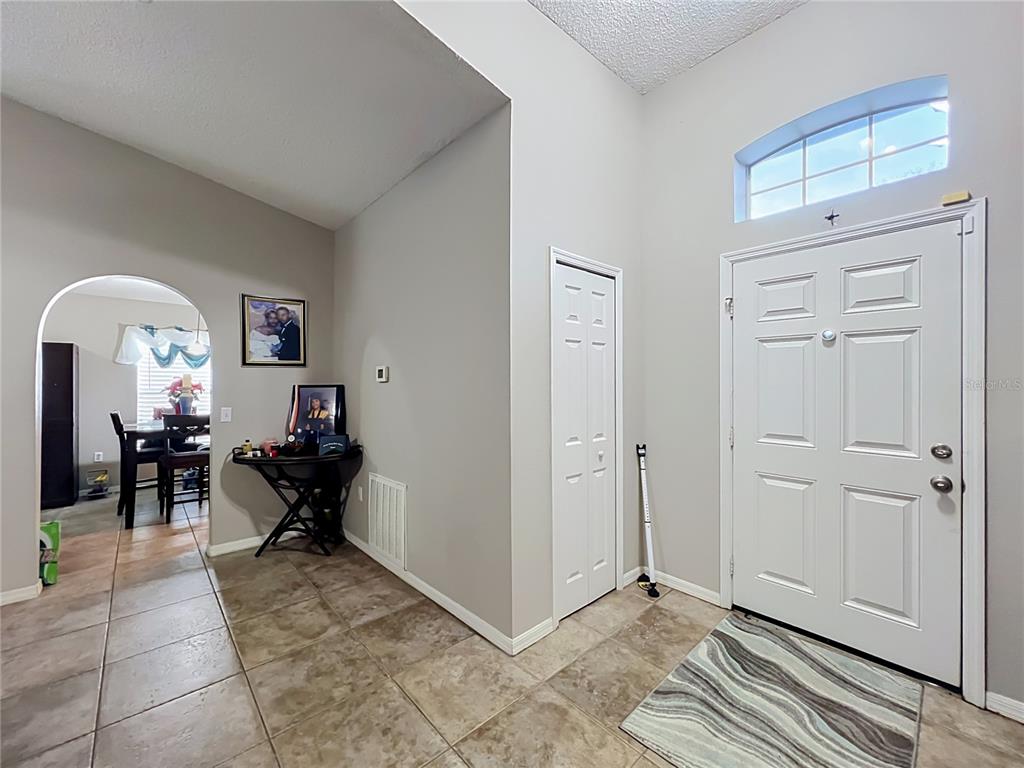 A tiled entryway features a white front door, a bi-fold closet, and an arched doorway — 2131 CORNER SCHOOL DRIVE, ORLANDO, FL