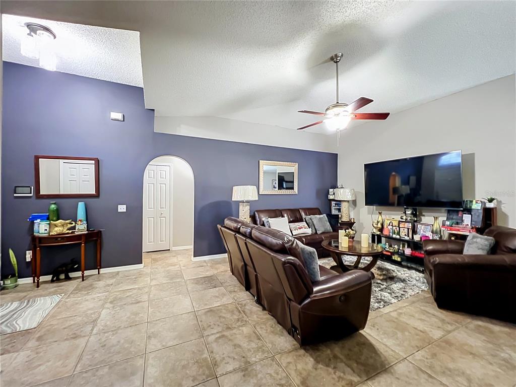 A living room features dark blue accent walls, tile flooring, leather furniture, and a ceiling fan — 2131 CORNER SCHOOL DRIVE, ORLANDO, FL