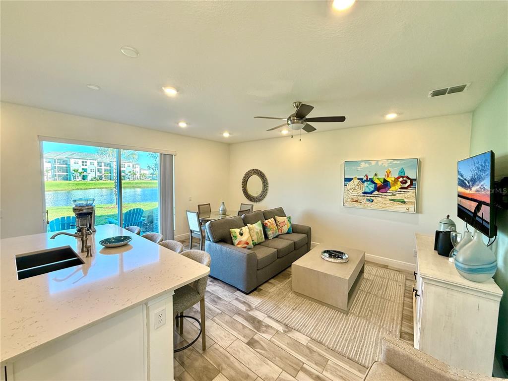 An open-concept living room and kitchen featuring light wood-look flooring and a view of water — 3117 CARIBBEAN SOUL DRIVE, KISSIMMEE, FL