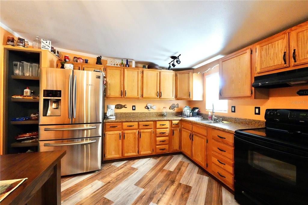 A kitchen features light wood cabinets, stainless steel appliances, speckled countertops, and wood-look flooring — 7494 GORDON LOOP, BROOKSVILLE, FL