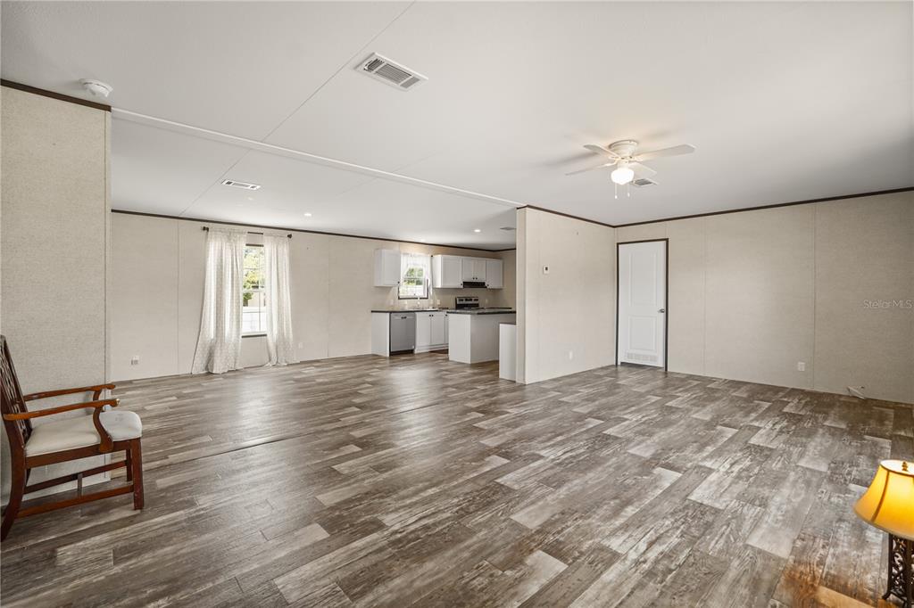 An open-concept living and kitchen area features wood-look flooring and a white kitchen island — 618 1 ST STREET, POLK CITY, FL