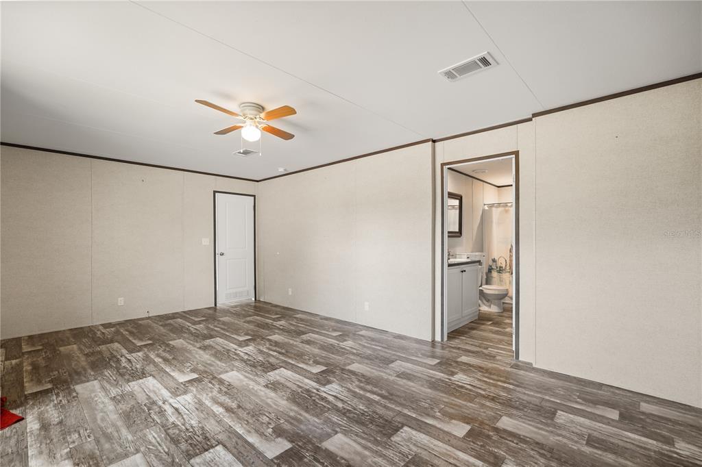 An open-concept room features wood-look flooring, a kitchen area, and a living space with curtains — 618 1 ST STREET, POLK CITY, FL