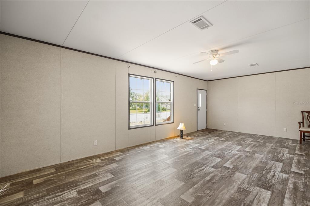 An open-concept living area features wood-look flooring, light-colored walls, and a view of an entryway — 618 1 ST STREET, POLK CITY, FL