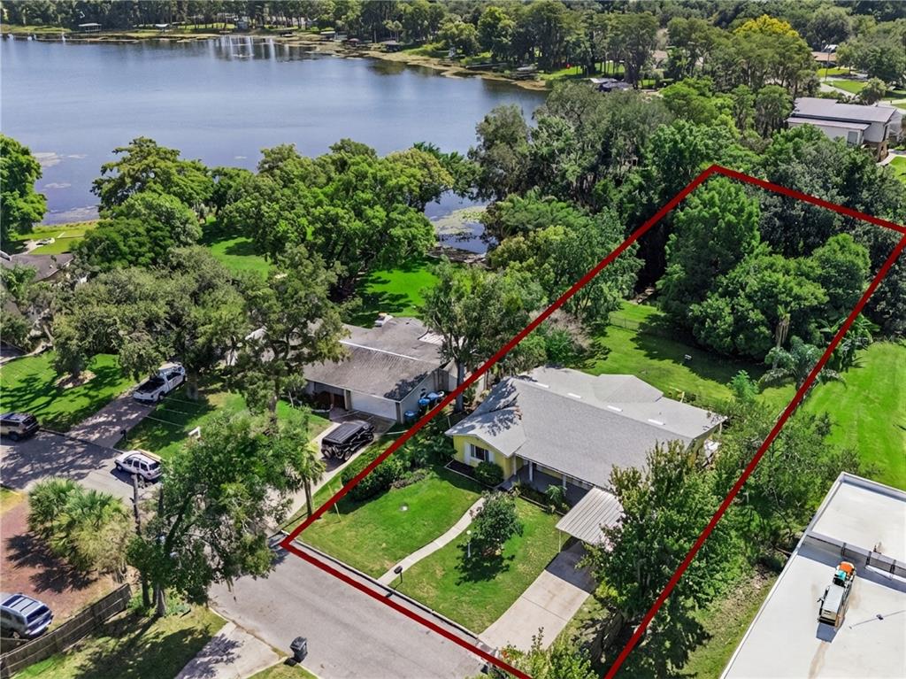 An aerial view shows a single-story house with a large backyard bordering a lake — 1003 LAKE BELL DRIVE, WINTER PARK, FL