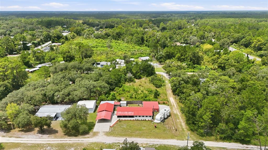 An aerial view shows a house with a red metal roof and an attached carport — 44945 2ND STREET, DELAND, FL