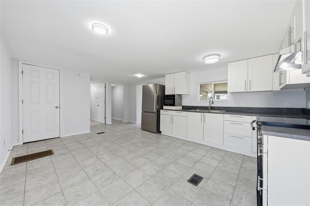 A kitchen with white cabinets, stainless steel appliances, and gray tile flooring — 44945 2ND STREET, DELAND, FL