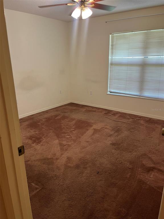 A bedroom features brown carpet, a window with blinds, and an open bi-fold closet door — 8451 SW 14TH LANE, OKEECHOBEE, FL