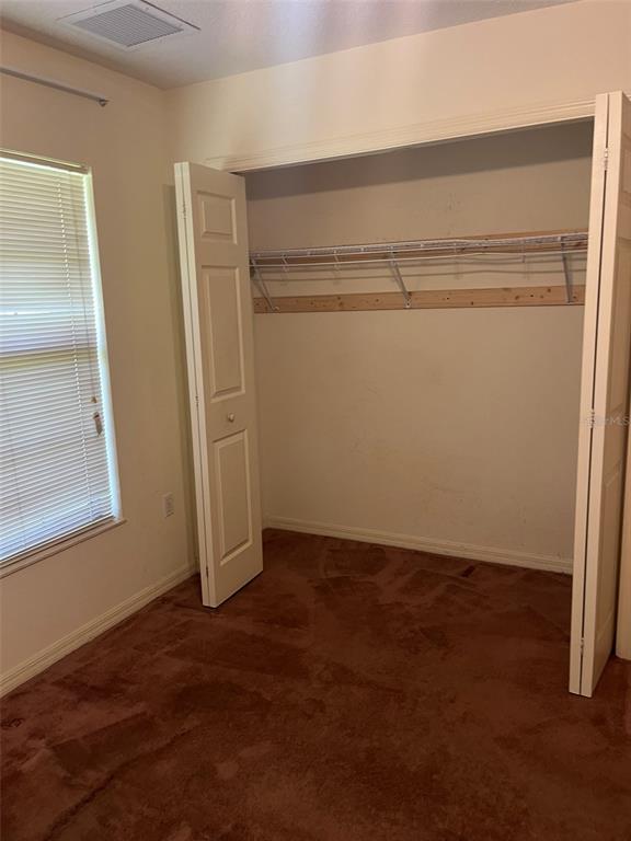 A room with beige walls, brown carpet, and a window covered by horizontal blinds — 8451 SW 14TH LANE, OKEECHOBEE, FL