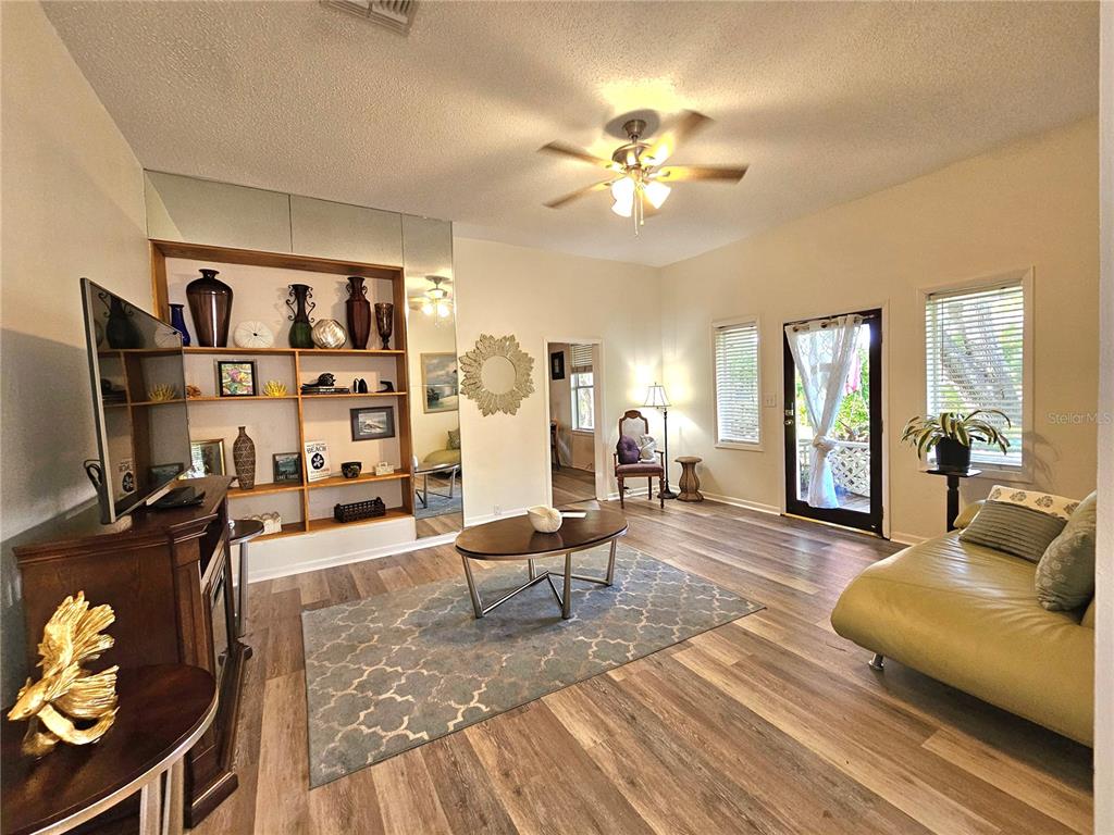 A living room features wood-look flooring, a built-in shelving unit, and a ceiling fan — 1500 N OSCEOLA AVENUE, CLEARWATER, FL