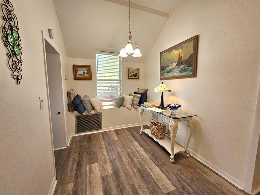 A sunlit nook features a window seat, wood-look flooring, a console table, and a chandelier — 1500 N OSCEOLA AVENUE, CLEARWATER, FL