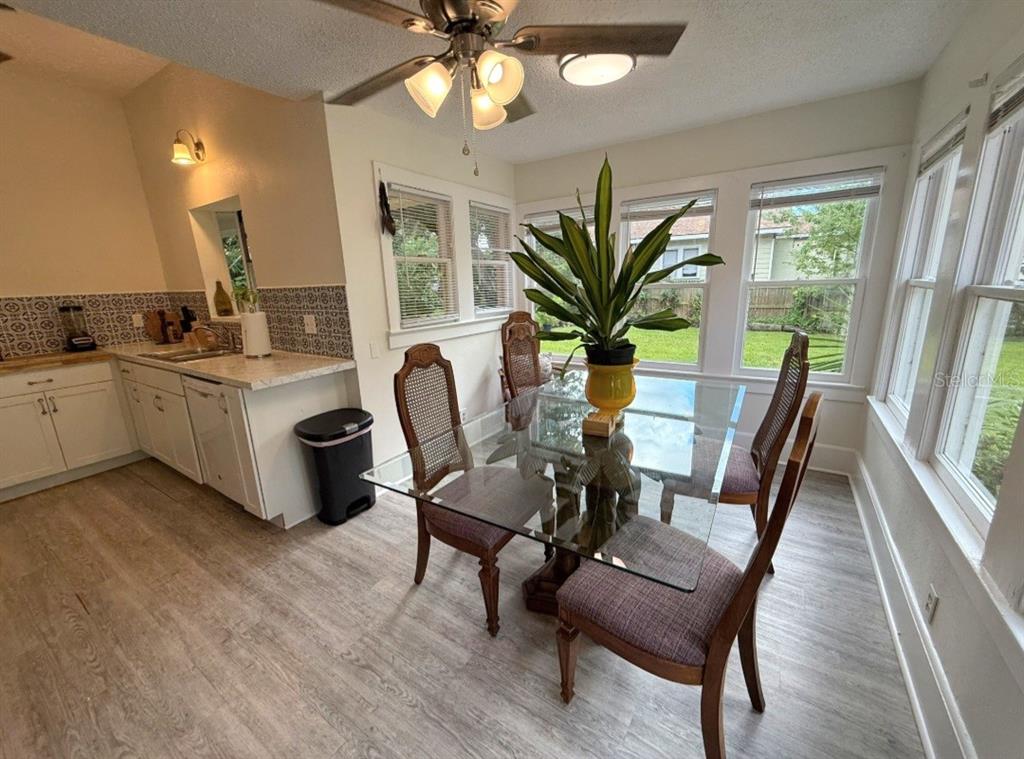 A dining area with a glass table, cane-back chairs, and a kitchen with patterned backsplash — 1500 N OSCEOLA AVENUE, CLEARWATER, FL