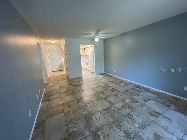 A living area with light blue walls and tan tile flooring leads to a kitchen — 2780 PARK DRIVE UNIT K-11, CLEARWATER, FL