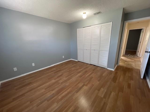 A bedroom with gray walls, wood-look flooring, and white louvered closet doors — 2780 PARK DRIVE UNIT K-11, CLEARWATER, FL