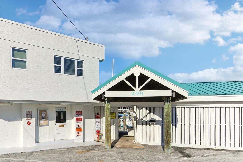 A white building with a green roof and a covered entrance featuring the number 200 — 200 WINDWARD PASSAGE UNIT 84, CLEARWATER, FL