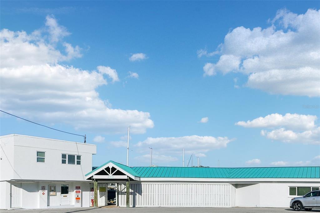 A white building with a teal metal roof stands under a bright blue sky — 200 WINDWARD PASSAGE UNIT 84, CLEARWATER, FL