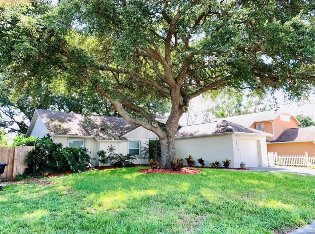 A single-story house with a large oak tree in the front yard and a garage — 7333 RADIANT CIRCLE, ORLANDO, FL