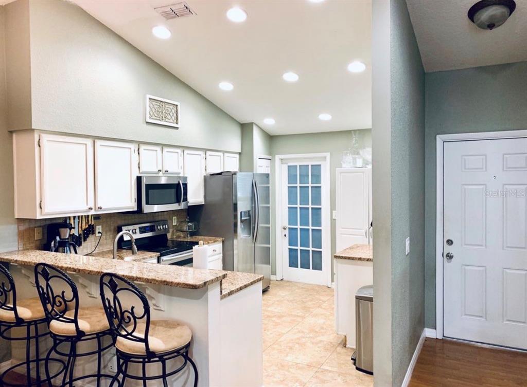 A kitchen with white cabinets, granite countertops, stainless steel appliances, and a breakfast bar — 7333 RADIANT CIRCLE, ORLANDO, FL