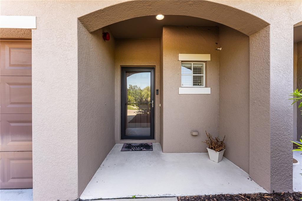 A covered concrete entryway features a glass storm door, a small window, and a planter — 1346 GRANTHAM DRIVE, SARASOTA, FL