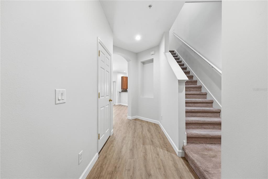 An interior hallway features light wood-look flooring, a carpeted staircase, and a white door — 1346 GRANTHAM DRIVE, SARASOTA, FL