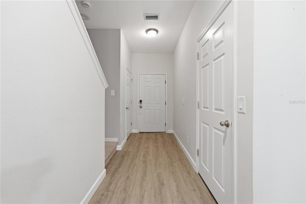 A bright entryway features light wood-look flooring, white walls, and three white interior doors — 1346 GRANTHAM DRIVE, SARASOTA, FL