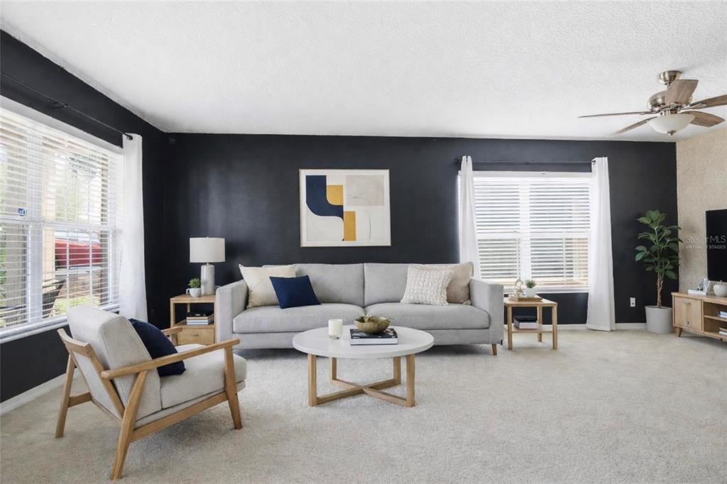 A living room features a grey sofa, an armchair, and black walls with white trim — 2463 MARTINS RUN, TAVARES, FL