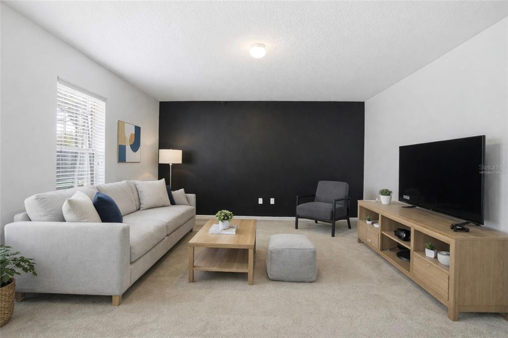 A living room features a black accent wall, light-colored sofa, and wood media console — 2463 MARTINS RUN, TAVARES, FL