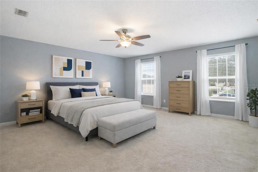 A bedroom features a gray bed, light wood furniture, and two windows with white curtains — 2463 MARTINS RUN, TAVARES, FL