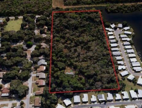 An aerial view shows a rectangular, wooded plot of land outlined in red — 5001 WHIPPOORWILL DRIVE, HOLIDAY, FL