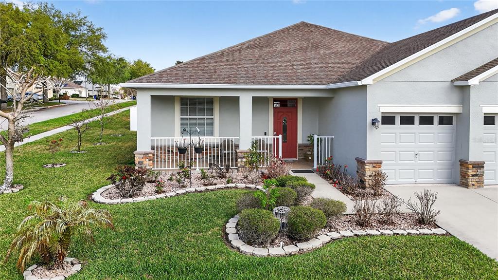 A single-story house features a red front door, a covered porch, and a stone-accented garage — 5269 ROYCE DRIVE, MOUNT DORA, FL