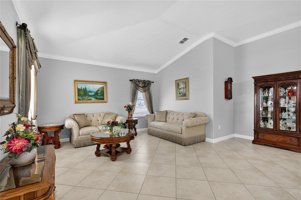 A living room features light gray walls, tile flooring, two sofas, and a wooden display cabinet — 5269 ROYCE DRIVE, MOUNT DORA, FL
