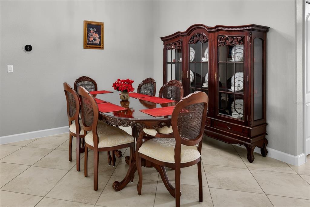 A dining room features a dark wood table with six chairs and a matching china cabinet — 5269 ROYCE DRIVE, MOUNT DORA, FL