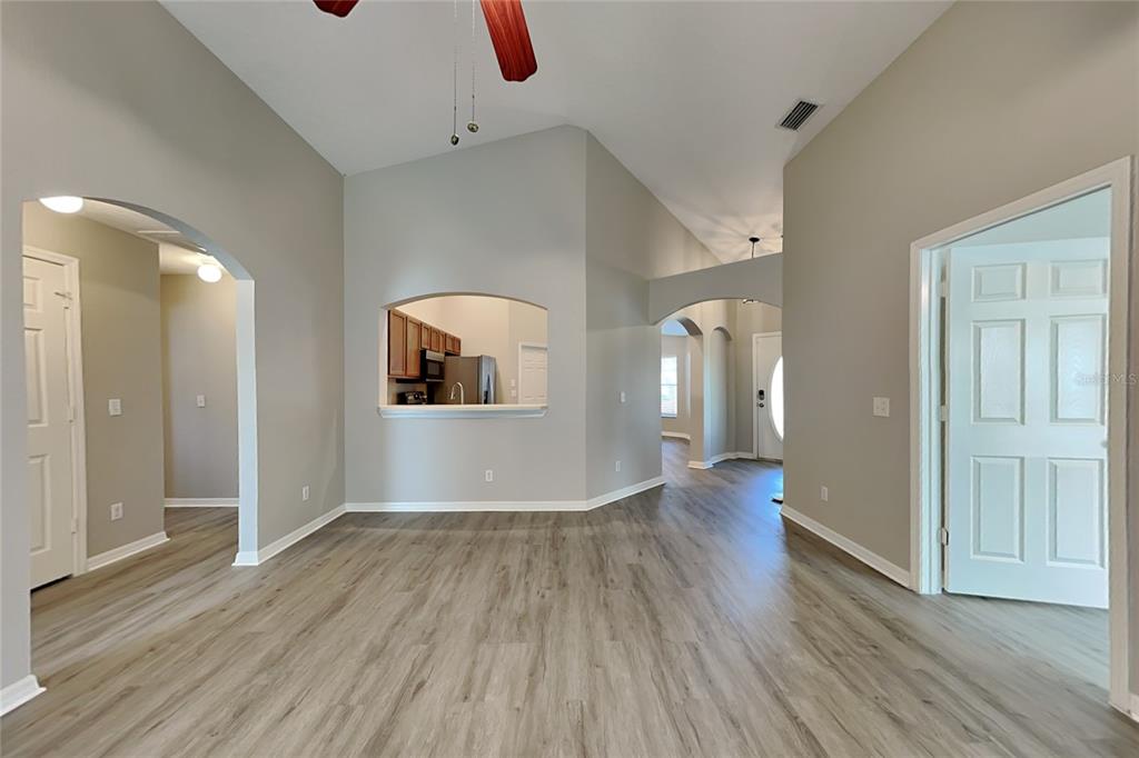An interior view of a living area with light gray walls, wood-look flooring, and arched openings — 3111 BUCKEYE POINTE DRIVE, WINTER HAVEN, FL